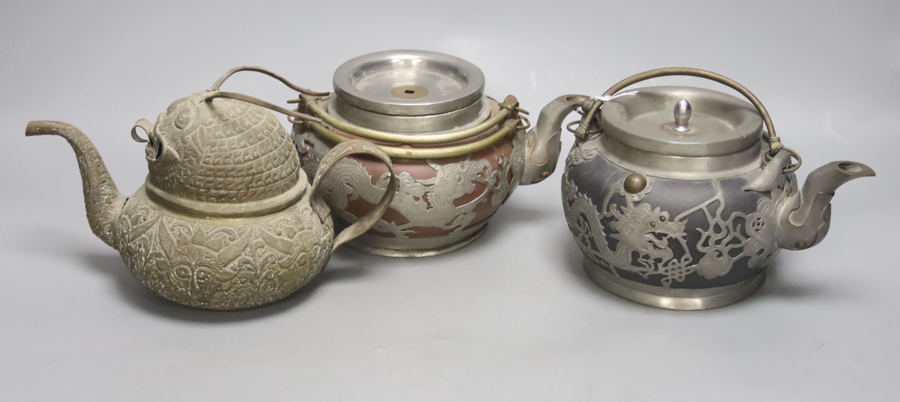 A trio of Chinese pewter mounted Yixing teapots